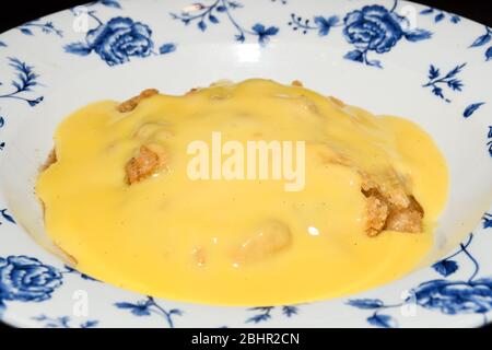 Tarte traditionnelle aux pommes anglaise avec pudding à la vanille, servie dans une assiette de style ancien Banque D'Images