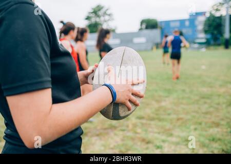 Un groupe de femmes et leur entraîneur masculin au rugby, une femme tenant un ballon de rugby. Banque D'Images