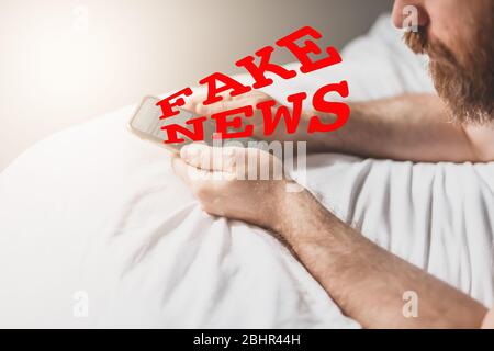 Fausses nouvelles infodemics pendant le concept de pandémie de Covid-19. Les mains de l'homme tenant le téléphone mobile lire les nouvelles mondiales ou le réseau social à la maison. Lire la dernière actualité Banque D'Images