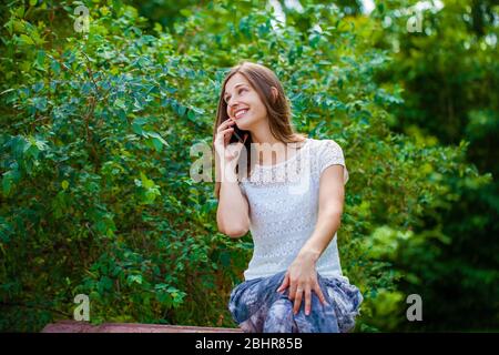 Portrait de la belle brune jeune femme parlant au téléphone mobile d'été à Green Park Banque D'Images