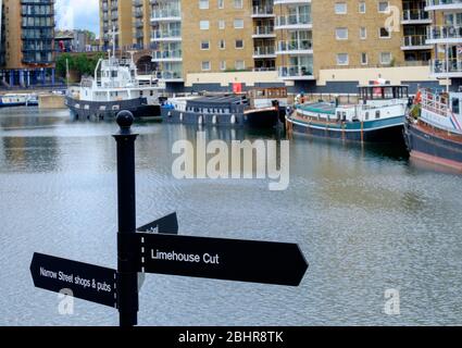 Panneau pour les boutiques et pubs Limehouse Cut & Narrow Street avec bateaux amarrés et haut-risques résidentiels en arrière-plan à Limehouse Marina, East London, UK Banque D'Images