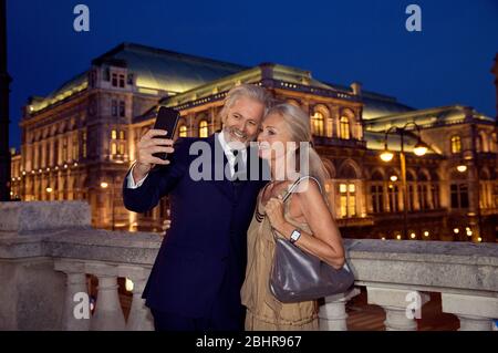 Un couple plus âgé prenant un selfie pendant une soirée à Vienne. Banque D'Images