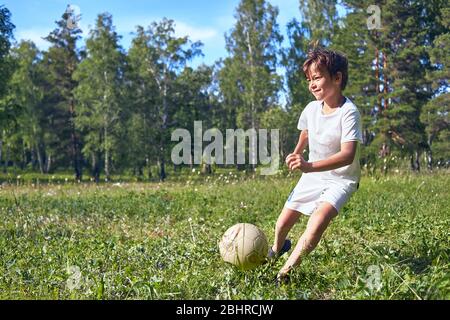 Kid botter un ballon de soccer sur le terrain Banque D'Images