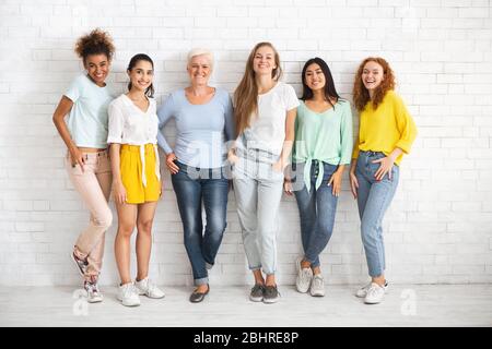 Diverses femmes de différentes âges se tenant sur le mur blanc de brique Banque D'Images