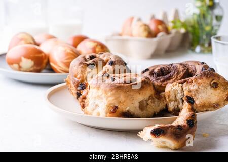 Table de brunch de Pâques. Petits pains à la cannelle, naturellement teint avec des coquilles d'oignon et des plantes printanières œufs de Pâques dans une boîte en carton, plantes printanières, zéro était Banque D'Images