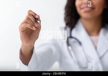 Médecin africain féminin tirant quelque chose sur l'espace de copie, en utilisant PAN Banque D'Images