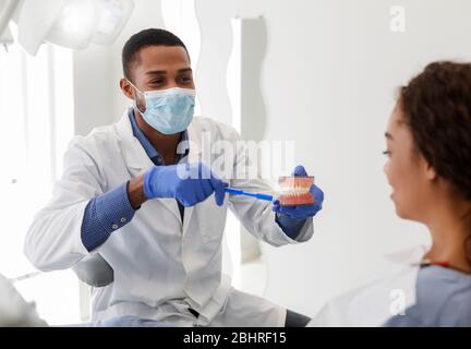 Jeune dentiste montrant la brosse à dents et le modèle de mâchoire du patient Banque D'Images