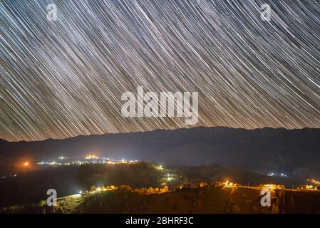 Des pistes étoiles au-dessus du village de Pestera dans les montagnes Piatra Craiului de Roumanie Banque D'Images