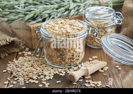 Pots de flocons d'avoine, oreilles d'avoine vertes et sac sur table en bois. Banque D'Images