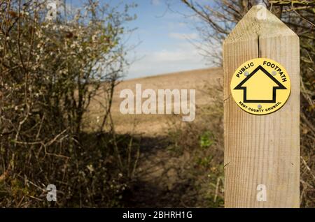 Panneau de sentier public jaune sur bois avec champ en arrière-plan, Kent Angleterre. Banque D'Images