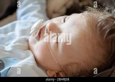 Bébé garçon avec la paralysie cérébrale obtient de l'oxygène par des broches nasales pour assurer la saturation en oxygène. Cathéter nasal dans un enfant patient à l'hôpital. Respirateur Banque D'Images