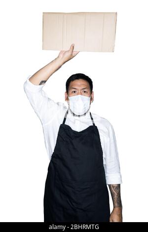 Barbu asiatique homme serveur, chef vêtu d'un tablier noir avec masque médical tient carton en blanc. Le concept de protestation, attention, re Banque D'Images