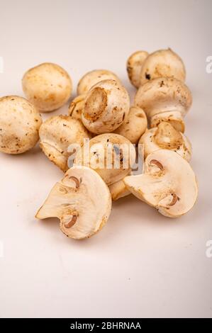 Moitiés de jeunes champignons coupés et de jeunes champignons dispersés sur un fond blanc. Gros plan Banque D'Images