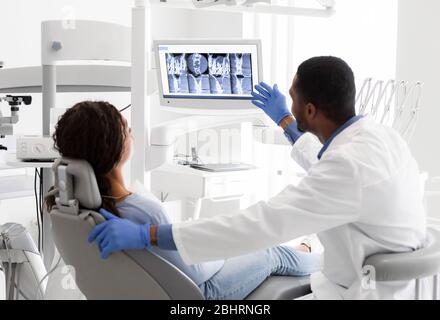 Dentiste expliquant à l'écran les rayons X au patient féminin Banque D'Images