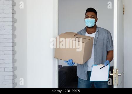 Livraison pendant le Coronavirus. Noir Courier porter masque de protection livré colis à la maison Banque D'Images