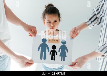 l'accent sélectif des parents tenant du papier avec la famille dessinée et le lettrage aimany près de l'enfant africain américain adopté sur le blanc Banque D'Images