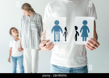 homme tenant du papier déchiré avec la famille dessinée près de la femme et adopté afro-américain kid sur blanc Banque D'Images