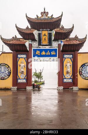 Fengdu, Chine - 8 mai 2010 : architecture marron, bleue et jaune de la porte du terminal de bateaux de la rivière Yangtze contre le ciel brumeux de silve. Un peu de feuillage vert sur le feuilles de feuilles Banque D'Images