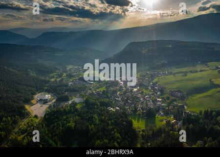 Vue aérienne de prairies vertes improbables des Alpes italiennes, paysage urbain de Bolzano, immenses nuages sur une vallée, toits de maisons, Dolomites en arrière-plan Banque D'Images
