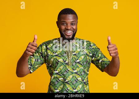 Un gars noir heureux dans un maillot vert africain montrant les pouces vers le haut Banque D'Images