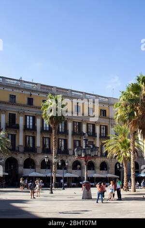 Vue sur les personnes accrochées sur une célèbre place de la ville appelée « Placa Reial », palmiers et bâtiments historiques traditionnels à Barcelone. C'est ensoleillé Banque D'Images