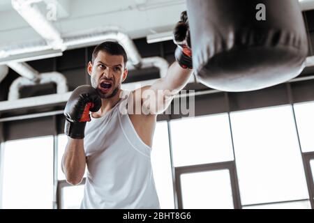 foyer sélectif de l'homme en colère dans des gants de boxe exercice avec sac de poinçonnage Banque D'Images