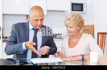 Femme mature et d'remplit dans les documents pour l'achat de biens dans la cuisine Banque D'Images