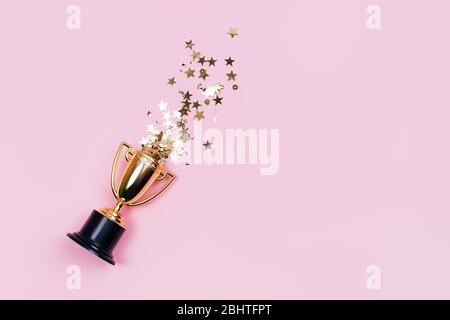 Une tasse gagnante avec des taches dorées sur un fond pastel. Bannière avec espace de copie. Style plat. Banque D'Images