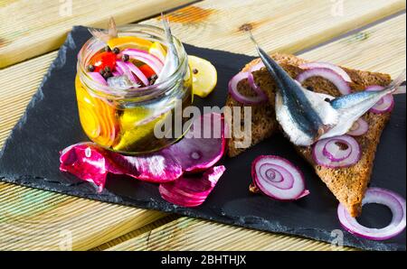 Des anchois marinés avec des oignons, betteraves, mélange de poivrons et de marinade au citron, vinaigre, huile d'olive et sel de mer. Servi sur pain noir à l'oignon Banque D'Images