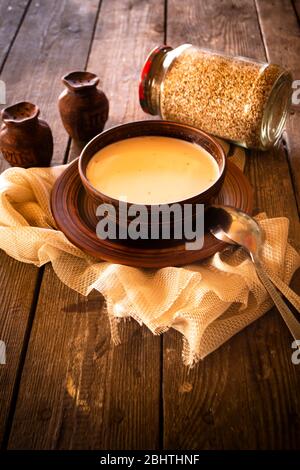 Sarrasin bouilli avec du lait dans un bol en bois sur une table en bois rustique, verticale Banque D'Images