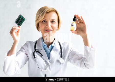 médecin heureux et mûr en flacon de conservation de manteau blanc avec lettrage cbd et blister avec des pilules en clinique Banque D'Images