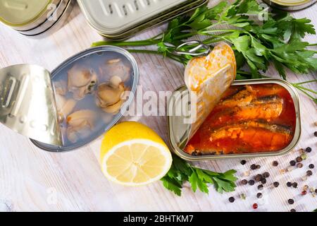 Boîtes de conserves avec palourdes et poissons, différents fruits de mer ouverts et fermés en conserve sur fond Banque D'Images