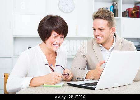Maman et fils heureux d'envisager un nouveau logiciel sur ordinateur portable assis à table Banque D'Images