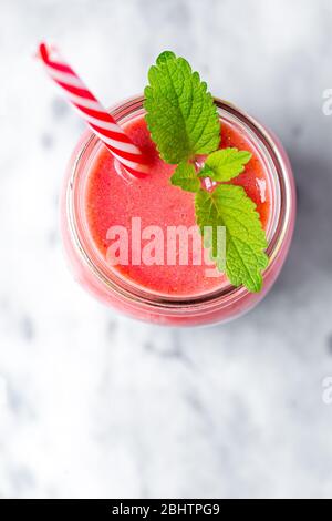 Vue en hauteur d'un smoothie aux fraises avec garniture de baumes au citron sur une surface marbrée Banque D'Images