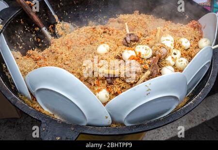 Cuisine appétissant pilaf oriental traditionnel dans un grand chaudron extérieur Banque D'Images