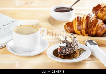 Petit-déjeuner continental avec croissants au chocolat frais, gâteau fait sous forme de souris et café sur fond de bois. Délicieuses pâtisseries avec c Banque D'Images