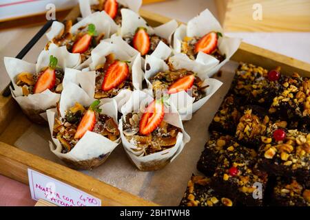 Muffins au chocolat fraîchement cuits avec noix, fraises et noix de coco exposés dans la pâtisserie Banque D'Images