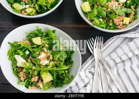 Salade de limonie à l'Arugula avec couscous, concombres et feta : salade d'arugula avec morceaux de concombre, morceaux de fromage feta et couscous de perle de blé entier Banque D'Images