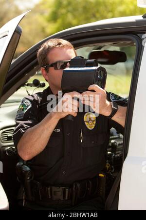 Austin Texas Etats-Unis, 6 avril 2011: Un policier utilise un pistolet radar pour surveiller la vitesse le long de l'autoroute au Texas. ©Marjorie Kamys Cotera/Daemmrich Photographie Banque D'Images