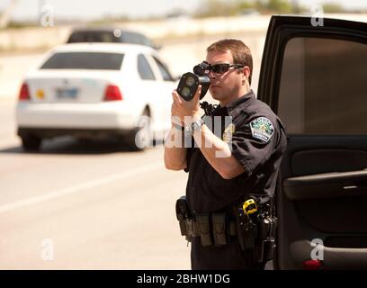 Austin Texas Etats-Unis, 6 avril 2011: Un policier utilise un pistolet radar pour surveiller la vitesse le long de l'autoroute au Texas. ©Marjorie Kamys Cotera/Daemmrich Photographie Banque D'Images