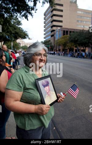 Austin, Texas États-Unis, 11 novembre 2010: Une femme d'âge moyen porte un petit drapeau américain et une photo de son frère, qui a été tué au Vietnam en 1969, lors du défilé annuel de la fête des anciens combattants sur l'avenue du Congrès vers le Capitole de l'État. © Bob Daemmrich Banque D'Images