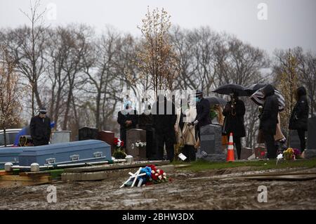 Boston, Massachusetts, États-Unis. 27 avril 2020. Le COVID-19, Corona virus, dans le Massachusetts est le troisième état le plus touché en Amérique. Une famille fait le plein de deux êtres chers dans le cimetière de Calvary dans le quartier de Dorchester à Boston, sous la pluie, le lundi 27 avril 2020. Crédit: Allison Dinner/ZUMA Wire/Alay Live News Banque D'Images