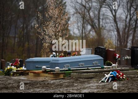 Boston, Massachusetts, États-Unis. 27 avril 2020. Le COVID-19, Corona virus, dans le Massachusetts est le troisième état le plus touché en Amérique. Une famille fait le plein de deux êtres chers dans le cimetière de Calvary dans le quartier de Dorchester à Boston, sous la pluie, le lundi 27 avril 2020. Deux coffrets attendent d'être abaissés dans le sol. Crédit: Allison Dinner/ZUMA Wire/Alay Live News Banque D'Images