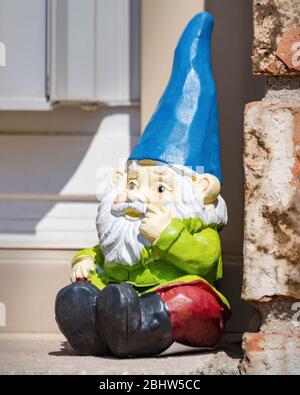 Gnome de jardin assis sur le seuil de fenêtre à l'extérieur. Banque D'Images