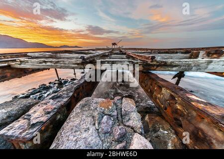 Ancien et historique quai de saltpeter à Taltal pendant le coucher du soleil avec des tons orange sur la structure rugueuse de chemin de fer Banque D'Images