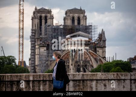 Paris, France. 27 avril 2020. Une femme passe devant la cathédrale notre-Dame en restauration à Paris, capitale de la France, 27 avril 2020. La rénovation de la cathédrale notre-Dame de Paris a repris lundi après une suspension depuis le 17 mars en raison de l'épidémie COVID-19, a annoncé l'agence publique chargée de superviser le projet. Crédit: Aurelien Morissard/Xinhua/Alay Live News Banque D'Images