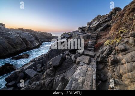 Un sentier magnifique et idyllique entre les rochers de granit en faisant un paysage fantastique d'un autre âge. Un pavé de pierre a coupé les falaises de la mer Banque D'Images