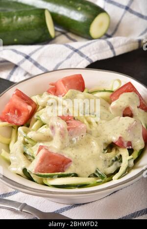 Pâtes courgettes spirales recouvertes de pesto de basilic sauce alfredo et tomates Banque D'Images