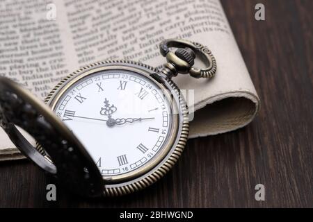 Montre de poche ancienne et journal sur table en bois sombre Banque D'Images