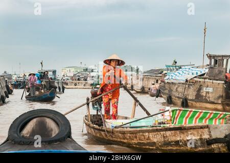 CAN Tho Vietnam - 14 octobre 2013 ; Femme en vêtements orange et chapeau conique faisant son chemin à travers les bateaux du marché flottant du Mékong Banque D'Images